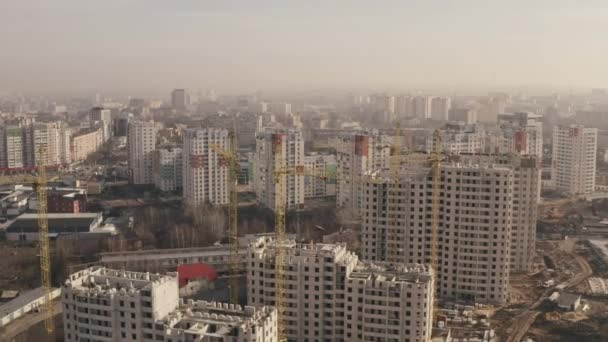 Aerial approaching shot of the construction of new buildings for housing, office buildings and construction yellow cranes in the city Kharkov, Ukraine. Top view of construction multi-storey buildings. — Stock Video