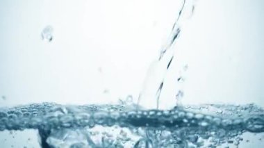  Yavaşça akan suyun pürüzsüz temiz yüzeyine düşmesi hava kabarcıkları, sıçramalar ve dalgalanmalar yaratıyor. Beyaz arkaplanda açık mavi bir sıvının tazeliği