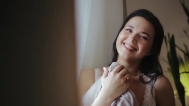 Battaniyeye sarılı seksi, beyaz dantelli iç çamaşırlı ve sabahları pencereden dışarı bakan güzel gülümseyen bin yıllık kadın için fotoğraf çekinme. Mutlu gelin yatak odasında işten eve dinleniyor..