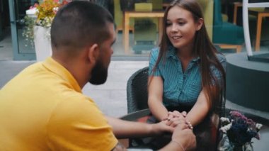 Birbirini seven genç ve sevimli çiftin romantik randevularının yakın plan görüntüsü dışarıdaki modern kafede oturmuş el ele konuşmanın keyfini çıkarıyorlar. Güzel bir kız restoranda sevgilisiyle vakit geçirir..