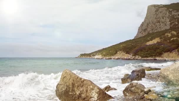 Magnifique laps de temps de petites vagues de mer s'écrasant sur des pierres côtières sur fond de ciel nuageux et de chaîne de montagnes en Crimée, en Ukraine. La tranquillité de la nature et la pacification. — Video