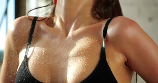 Nahaufnahme der Brust sexy athletische Fitness-Frau Modell Abkühlung mit etwas Wasser in isolierten Raum unter der Sonne. Sportliches süßes Mädchen entkommt Hitze mit kaltem Wasser nach Sportübungen im Sommer-Fitnessstudio. — Stockvideo