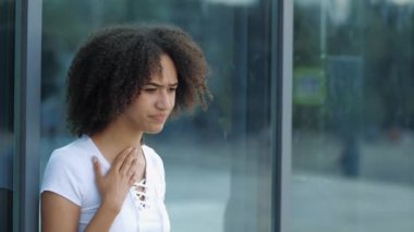 Afro-Amerikalı kızın boğazı ağrıyor, boynundan tutuluyor, sokakta hastalanıyor, kapanıyor. Soğuk algınlığı ve grip virüsünün ilk belirtileri ortaya çıktı. Kadın ağzını kapatır, elleri tutar, şehirde öksürür.