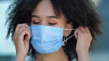 Güzel gülümseyen genç Afrikalı etnik kadın koruyucu maskesini çıkarıyor, gülümsüyor, derin derin nefes alıyor, grip salgınının sonunda seviniyor. Yabancı öğrenci karantina bittikten sonra hareket özgürlüğüne kavuştu