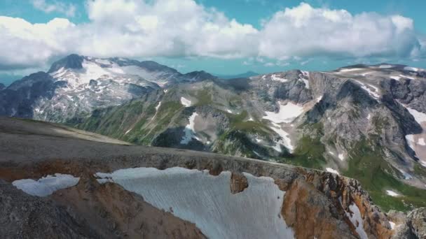 Luftbild der schönen kaukasischen Berge bedeckt Schnee unter großen Dampf von Wolken bei sonnigem Wetter am Morgen des Sommers, Adygea, Russland. Konzept von Reisen, Tourismus und Bergwandern. — Stockvideo