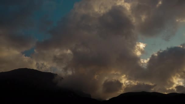 Foto aérea de la silueta de las cimas de las montañas caucásicas a la sombra bajo las enormes nubes arremolinadas a la luz del sol, Adygea, Rusia. Hermoso lapso de tiempo de la naturaleza en el paisaje del cielo y la roca . — Vídeo de stock