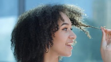 Yakından Afrikalı kız kıvırcık saçlı. Bukleli saçlar tutan, dişlek gülümseyen genç Amerikalı kadın. Saçı kabarık, saç fırçası, saçı kuru, saçları kırışmış, saçları kıvırcık.
