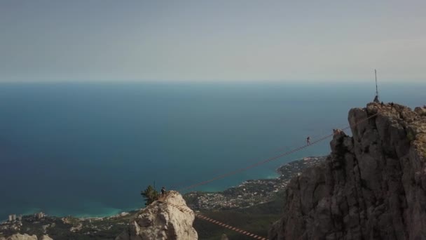 La montaña más alta famosa de la Crimea - la vista aérea Ai-petri, Yalta. Los turistas suben en un puente extremo a la cima contra el telón de fondo del Mar Negro y la ciudad de Alupka por debajo . — Vídeos de Stock