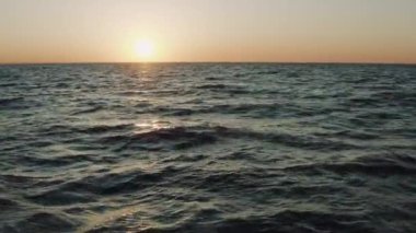 Sabaha karşı Kırım 'daki Karadeniz dalgaları üzerinde güzel bir uçuş. Yaz günbatımının altında okyanustaki harika suyun havadan görünüşü. Su rezervlerinin inanılmaz vahşi doğası..