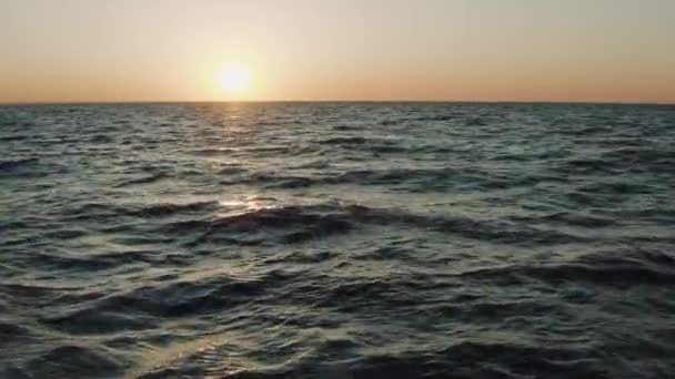 夜明けを背景にクリミアの黒海の波の上に美しい飛行。夏の夕日の下で海の素晴らしい水の空中ビュー。水の素晴らしい野生の自然旅行の準備. — ストック動画