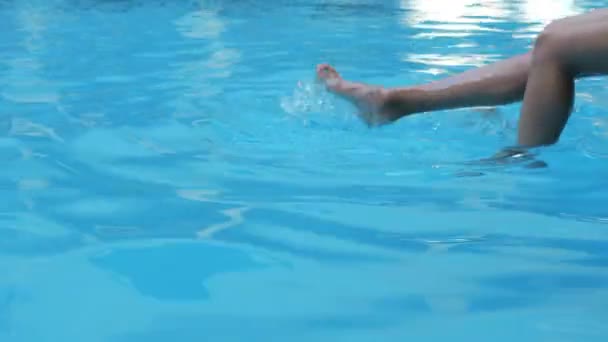 Dva páry štíhlé opálené mladé samice nohy visí třást v čisté teplé příjemné chladné osvěžující modré vody vytváří krásné skvrny a vlny v prázdném veřejném bazénu v zahraničí na slunné dovolené horký den — Stock video