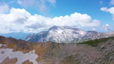Kafkasya 'nın destansı doğasının Oshten tepesinden Mountain Fisht' e kadar uzanan, kar taşları ve mavi gökyüzündeki beyaz bulutların altındaki çimlerle kaplı hava manzarası. Yaz, Adygea, Rusya. Ekoloji ve dünya rezervleri kaydediliyor.