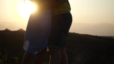 Sahada birbirine aşık genç çiftin güzel romantik akşam günbatımının tadını çıkarırken yazın, yavaş çekimde. Sevgi dolu bir erkek ve kızın şehir dışında doğada buluşması.