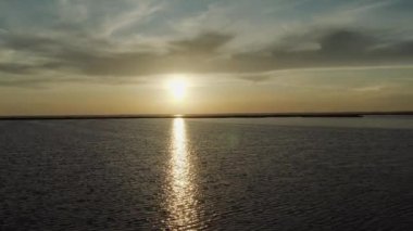 Kum siluetinin havadan görünüşü yaz mevsiminde deniz batımının arka planına tükürüyor. Adaların ve doğa rezervlerinin üzerinden destansı bir uçuş ve akşam gökyüzü ile gökyüzü..