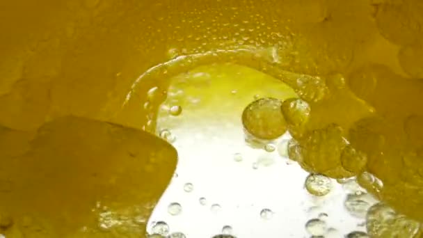 Aceite de refinería amarillo girasol mezclado con agua, no disolver. Las bombillas de aire de burbujas flotan en líquidos creando patrones, texturas y fondos elegantes. Lento movimiento del líquido de aceite de verter. Salud Vitamina E — Vídeo de stock