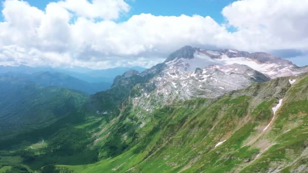 Vista aérea do vale entre belas montanhas do Cáucaso, deslumbrante desfiladeiro coberto com grama verde sob sombras flutuantes de nuvens. Voando sobre montanhas épicas Fisht Oshten Lago-Naki Plateau, Rússia — Vídeo de Stock