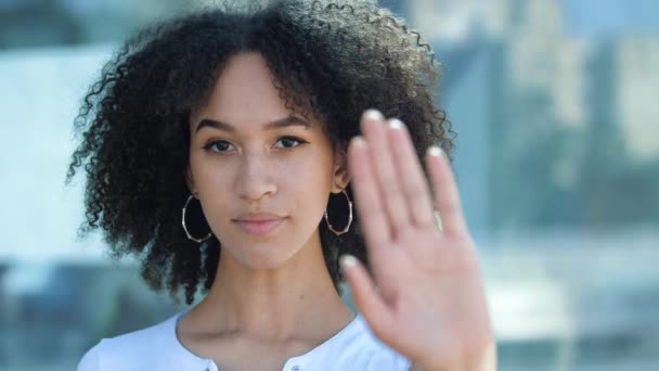 Серьёзная афроамериканка прикрывает себя ладонью, уверенно показывает запретительный жест, останавливается и не качает головой. Молодая этническая женщина против насилия, защищает личные границы. — стоковое видео