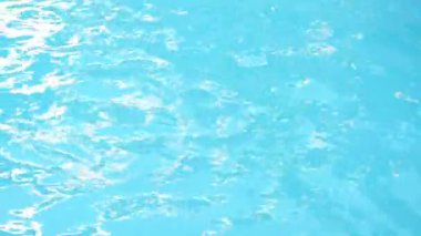 Sallanan dalgaların yakın görüntüsü, havuzda ya da denizde titreşen berrak soğuk suyun parlak yansımaları, arka planda parıldayan güneş ışığı, doğal doku, soyut çekim.