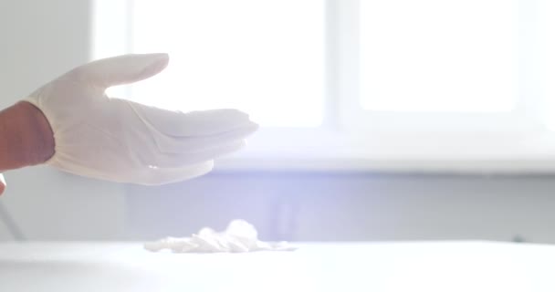 Primeros planos de las manos de las mujeres humanas poniéndose guantes de protección médica de látex de goma, previniendo la pandemia de infección por virus. Médico preparando los brazos para el examen o procedimiento en el hospital, detalles cerca — Vídeo de stock