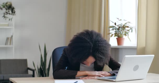 Trabalhadora estudante sobrecarregada dormindo na mesa com laptop sente dor de cabeça cansado. Funcionário improdutivo mulher de raça mista deitada na mesa adormecer sentindo tédio, precisa descansar, conceito de insônia — Vídeo de Stock