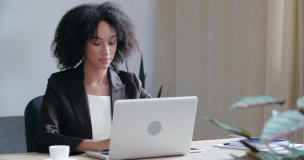 Σοβαρός Αφροαμερικάνος φοιτητής ελεύθερος επαγγελματίας φοράει μαύρο σακάκι κάθεται στο γραφείο στο σπίτι, πληκτρολογώντας στο πληκτρολόγιο laptop, σερφάροντας στο διαδίκτυο δίκτυο, επιτυχημένη εργασία σε απευθείας σύνδεση, κρατήσεις εισιτηρίων, κοντινό πλάνο — Αρχείο Βίντεο