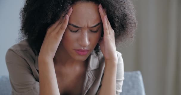 Curly naštvaný ustaraná dívka cítí stres a rozrušený, nemůže vyřešit špatnou situaci. Mladá afro-americká žena trpící bolestí hlavy slabá bolest, dáma držící své čelo s rukama v zármutku — Stock video