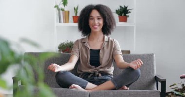 Genç etnik kız evde sabah nefes egzersizleri yapıyor, rahat koltukta yoga yapıyor, Asana Lotus insan vücudunda oturuyor, dinlenme sükunetini bozuyor, mutlu enerji uyum kavramını hissediyor.