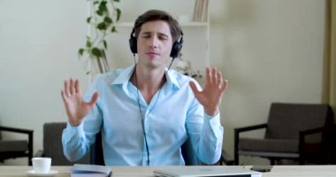 Mutlu iş adamı ofiste dinleniyor kablosuz kulaklıklarla müzik dinliyor, davul çalar gibi kollarını hareket ettiriyor, şarkı söylüyor. Tişört giyen komik bir erkek sıkılır, rahatlamak için neşeli dans eder, sıkı çalışır.