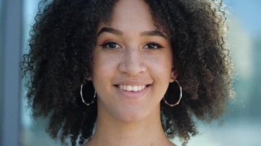 Mutlu çekici genç kız neşeyle gülüyor ve müdahaleci ile konuşuyor, bir diyalog kuruyor ve neşeli bir şekilde tartışıyor. Genç Afrikalı Amerikalı kadın dişlek, iletişim kuran, dostça gülümsüyor.