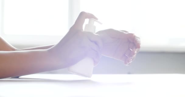 Κοντινό πλάνο γυναικεία χέρια εφαρμογή ενυδατική κρέμα στα χέρια κάθεται στο γραφείο στο σπίτι ή το γραφείο. Υγιής γυναίκα βάζοντας θρεπτικό απολυμαντικό οργανική λοσιόν για ξηρά δάχτυλα ενυδατική θεραπεία φροντίδας του δέρματος — Αρχείο Βίντεο