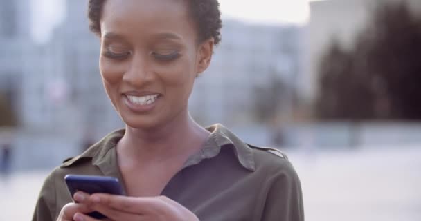 Tête tourné jeune dame américaine souriant toothy, visage humain féminin heureux, regardant dans smartphone moderne mobile, tapant un message au téléphone, bavarder avec des amis garçons, rendez-vous en ligne sur le réseau social — Video