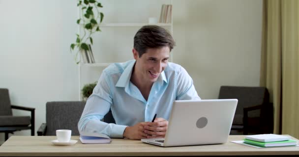 笑顔の古典的な男はオフィスの自宅でテーブルに座って、家族の友人と通信するためにラップトップのWebカメラを使用して、積極的に手でビデオ会議ネットワークジェスチャーで話す、答えインターネットコール — ストック動画