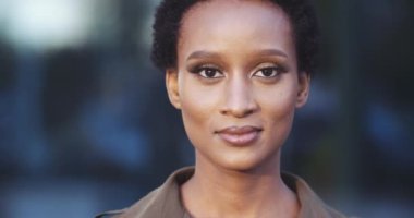 Genç, melez, Afro-Amerikalı, Afro saçlı, kısa saçlı, siyah bir kadının ön planda çekilmiş portresi. Kameraya dost canlısı bakıyor. İnsan yüzü, ideal doğal makyaj konsepti.