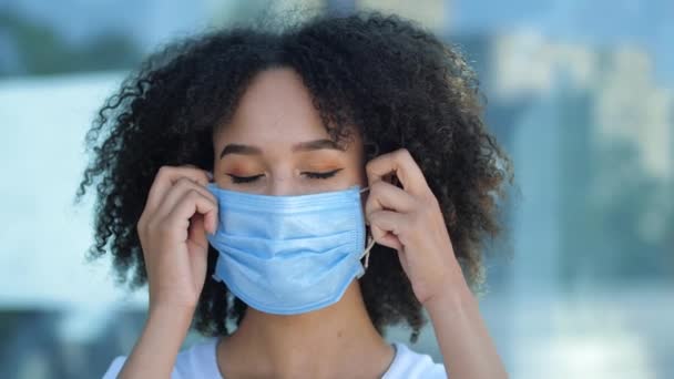 Bella sorridente giovane donna afroamericana toglie la maschera medica protettiva dal viso, respira profondamente. Inspirare aria fresca in strada, guardare in camera all'aperto. Fine del focolaio di coronavirus influenzale — Video Stock