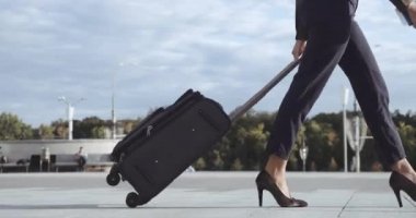 Afro-Amerikalı iş kadını havaalanı terminalinden bagajıyla taksi parkına gidiyor. Karışık ırk klasik kızı, topuklu ayakkabıyla sokağa çıkıyor, bavulları topluyor, seyahat konsepti, tepeden tırnağa ateş ediyor.