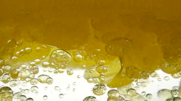 El aceite de motor de la máquina mezclado con agua y aceite de refinería amarillo girasol no se disuelve. Las bombillas de aire de burbujas flotan en líquidos creando patrones elegantes, fondo de textura. Lento movimiento del líquido lubricante de verter — Vídeos de Stock