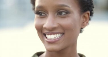 Cana yakın, samimi, genç bir melez yüzü makyajlı, siyah gözlü, kıvrımlı kirpikli, Afro etnik kadın portresi şehir sokaklarında geniş beyaz dişlerle gülümseyen.