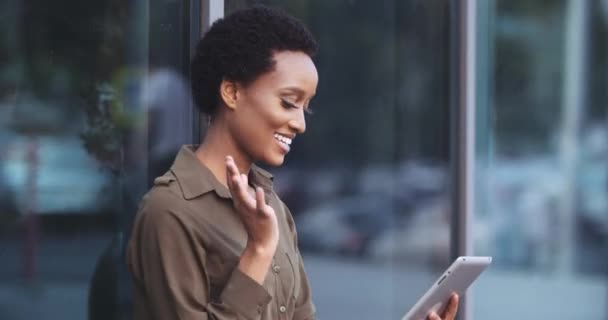 Femme d'affaires américaine pigiste tient tablette d'ordinateur, utilise un appareil numérique pour répondre à l'appel vidéo, communique dans des conférences en ligne, flux sur les réseaux sociaux, vagues main dans le geste de bienvenue — Video