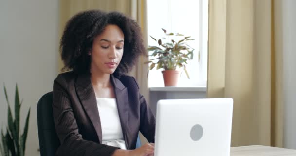 Cansada jovem empresária fazendo horas extras no laptop, sentindo exaustão, tontura, pressão, precisando de descanso. Menina afro-americana perturbada tem estresse dia duro, segurando a cabeça com as mãos na dor — Vídeo de Stock