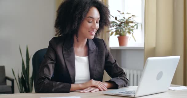 Radosny młody mieszany wyścig bizneswoman freelancer w czarnej kurtce trzymając wideo rozmowy online z przyjaciółmi lub klientami za pomocą aplikacji na laptopa, pracujący tłumacz zdalnie z domu, nauczanie języków — Wideo stockowe