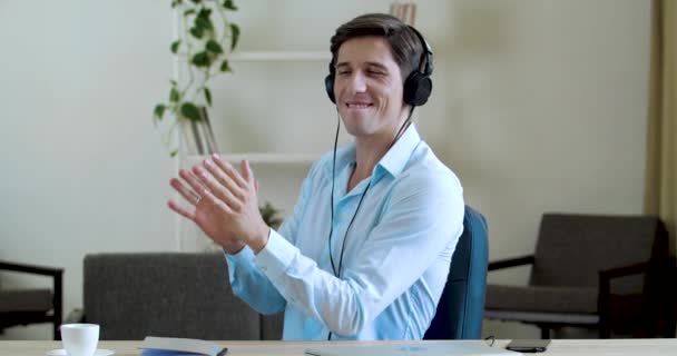 Funny empresario estudiante trabajador se sienta a la mesa en los auriculares, escucha música, hace olas con las manos, baila en la sala de oficina en casa durante el descanso, primer plano. Cómic joven gerente loco se relaja al sonido — Vídeos de Stock