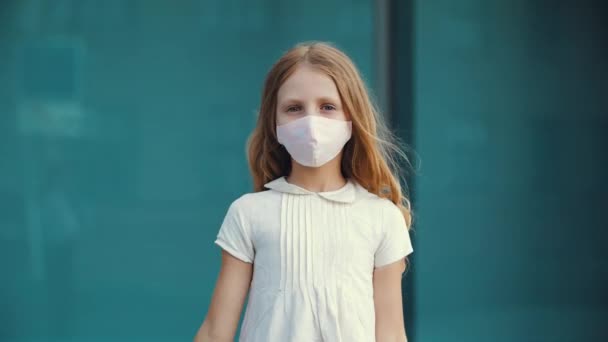 小さな女の子は、ウイルスから保護医療マスクを身に着けています,カメラに親指を示しています,同意の兆候,概念のような,満足の象徴,自由の喜び,学校は、検疫パンデミックのためにキャンセル — ストック動画
