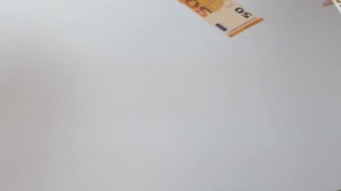 Avro banknotları beyaz arka plana karşı havayı yavaş çekimde yükseltiyor. Avro düzgünce uçmaya başlıyor.