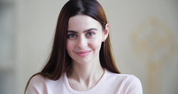 Porträt einer attraktiven jungen kaukasischen Millennial-Frau mit langen Haaren. Großaufnahme des weiblichen Gesichts, das in die Kamera schaut, freundliche, weit geöffnete Augen, süß lächelnd, fröhliche Freude verlegen — Stockvideo