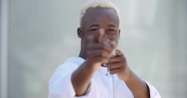 Portrait of smile stylish African American mixed race guy man in white clothes pointing with fingers to camera, gestur of approval greeting support, make hands in front of him, indicate direction — Stok Video