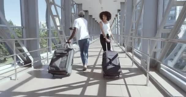 Casal de afro-americanos dois amantes adolescentes ir ao terminal do aeroporto, transportar malas com bagagem, dançar com bagagem, desfrutar de viagens. Misturado irmão raça e irmã mover alegremente, celebrar o regresso a casa — Vídeo de Stock