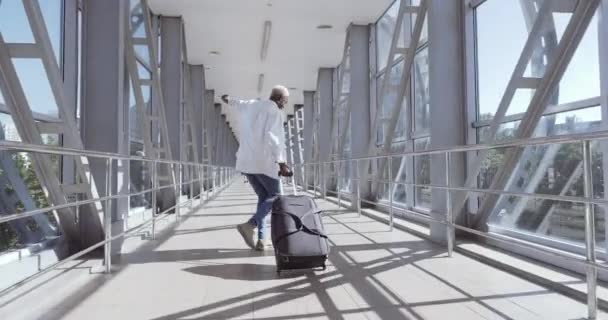 Africano cara elegante moda misto raça modelo homem carregando bagagem mala, dançando sozinho no terminal do aeroporto, movendo-se para o trem de embarque, desfrutar de viagem no exterior, celebrando férias, fabricante de férias — Vídeo de Stock