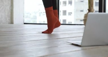 Kadın bacaklarında el yapımı kırmızı yün çoraplar, evde spor için dizüstü bilgisayara gidiyor modern bir aletle, çevrimiçi dersleri izliyor, dans etmeden önce ayaklarını tekrar ediyor.