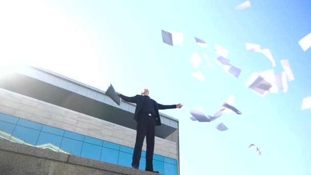 Mladý podnikatel manažer stojí na ulici na pozadí pronájmu kanceláře na hraně, rozhazuje papíry ve vzduchu, zahazuje dokumenty, cítí úlevu ze svobody poté, co byl vyhozen, roztahuje ruce na stranu — Stock video
