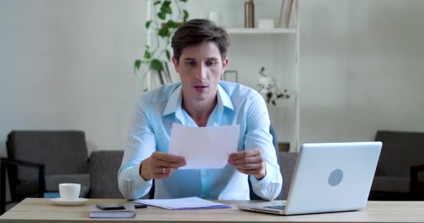 Sérieux jeune homme d'affaires concentré écrivain en chemise bleue est assis à table, écrit lettre avec stylo, signe l'ordre d'accord de document, fait erreur sur le papier, se fâche larmes jette note, concept d'échec — Video